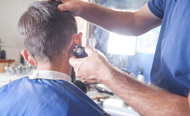 Professional hairdresser using hair cutting machine.