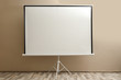 © New Africa - Blank projection screen near beige wall indoors. Space for design