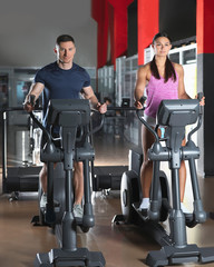 Canvas Print - Couple working out on elliptical trainers in gym