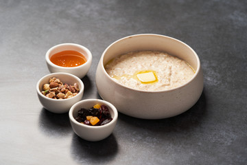 Wall Mural - Oatmeal porridge with raisins, honey and nuts in a bowl