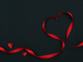 Top view of ribbon shaped as heart and red heart paper on black background with copyspace for valentine day, wedding, romantic concept.