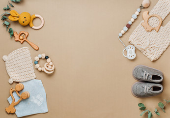 Frame of wooden toys, clothes and shoes on beige background