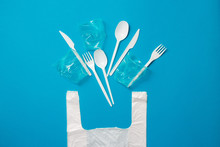 White Single-use Plastic Knives, Spoons, Forks And Bag On A Blue Background. Say No To Single Use Plastic. Environmental, Pollution Concept.