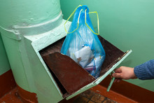 Throwing Out Garbage Packed In A Garbage Bag Using A Home Trash Chute In Russia