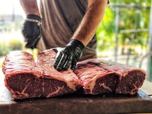 Midsection Of Man Cutting Meat On Table In Butcher Shop