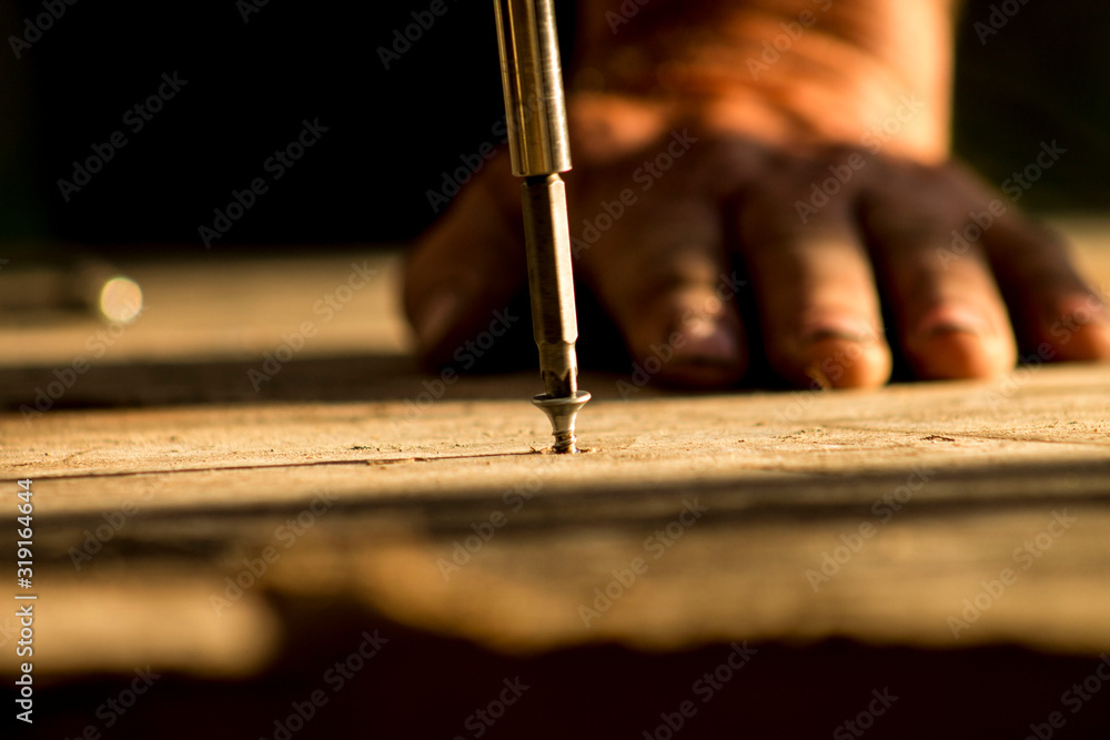 Close-Up Of Man Screwing Nail In Wood - obrazy, fototapety, plakaty 