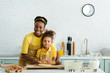cute african american kid and mother holding rolling pin near raw dough on cutting board