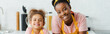 panoramic shot of happy african american mother and cute daughter looking at camera