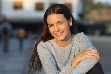 Wall Mural - Happy teenage girl sitting looking at camera in the street