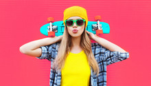 Portrait Cool Woman With Skateboard Wearing Colorful Yellow Hat On Pink Background