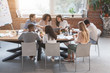 © Prostock-studio - Friendly business team sitting around table, having meeting
