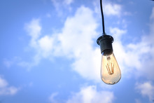 Low Angle View Of Illuminated Light Bulb Hanging Against Sky