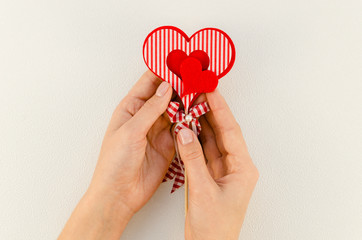 Top view feminine hands hold red felt hearts. Valentine's day and love concept on white background