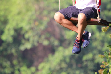 Adult legs sitting on swing  loneliness playing in the park playful and happy the outside background