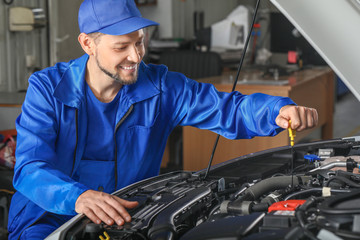 Wall Mural - Male mechanic checking level of oil in car engine