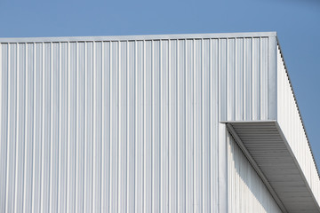 Sticker - metal sheet factory warehouse against blue sky background. silver corrugated steel industrial roof.