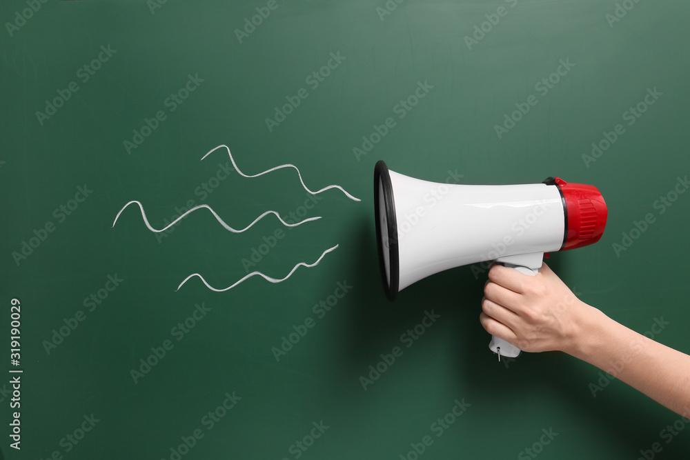 Female hand with megaphone on color background