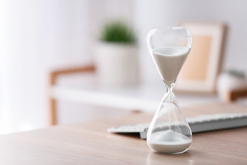 Wall Mural - Hourglass with computer keyboard on table in office. Time management concept