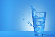 Glass of fresh water with splash on color background