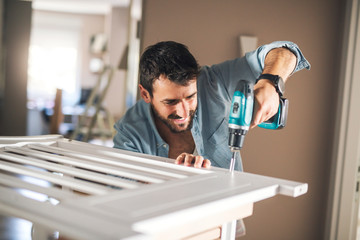 Wall Mural - Man installing baby crib.