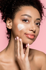 Wall Mural - portrait of smiling african american girl with heart of cream of cheek, isolated on pink