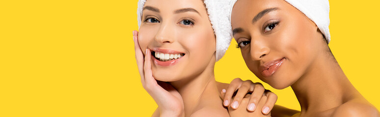 Wall Mural - panoramic shot of happy multiethnic girls with towels on heads, isolated on yellow