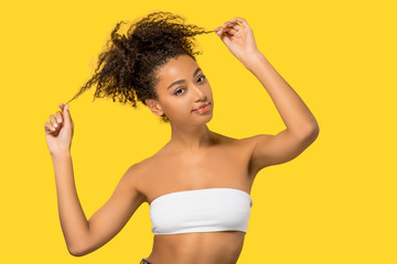 Wall Mural - portrait of smiling african american girl with curly hair, isolated on yellow