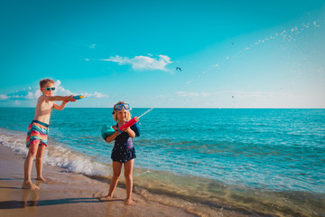 Poster - happy cute boy and girl play with water gun on beach