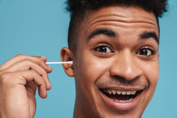 Wall Mural - Photo of excited african american man using cotton swab and smiling