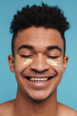 Wall Mural - Photo of excited african american man with under eye patches smiling