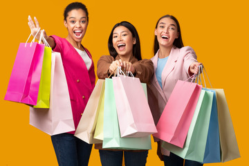 Three Excited Women Showing Colorful Shopper Bags, Studio Shot