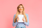 Cheering teen holding pen as moustache over pink wall