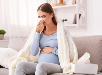 Wall Mural - Expectant Girl Blowing Nose In Tissue Sitting On Sofa Indoor