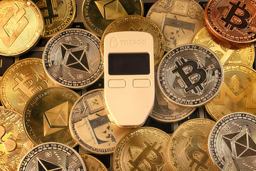 WROCLAW, POLAND - JANUARY 28, 2020: Physical version of Bitcoin (BTC), Trezor (cryptocurrency hardware wallet) and other cryptocurrencies background.