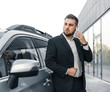 © klepach - Handsome businessman with smartphone near vehicle on office parking