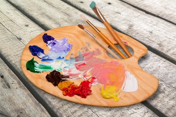 Wall Mural - Wooden art palette with blobs of paint and  brushes on desk