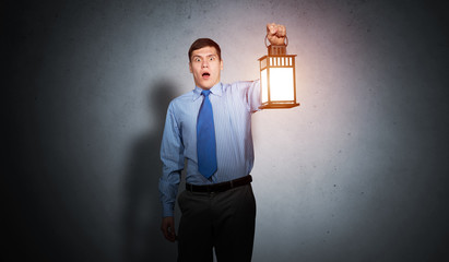 Horrified businessman holding glowing lantern