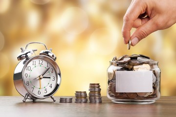 Wall Mural - Hand putting coins in a glass jar