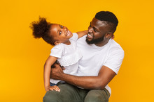 Playful Little Girl Posing With Her Dad Over Yellow Background