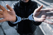Shallow depth of field (selective focus) image with the handcuffed hands of a man.
