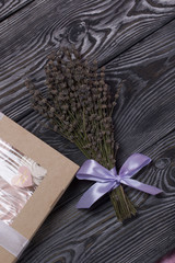 Marshmallow sandwiches in craft paper packaging. Tied with a ribbon with a bow. Nearby is a bouquet of dry lavender. On pine brushed boards painted in black and white.