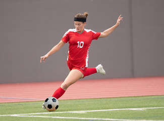 Young athletic girl playing soccer in a game