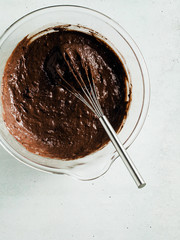 chocolate batter, ready to bake in a glass bowl with a whisk