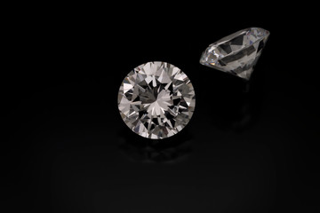 Wall Mural - A solitaire faceted, round diamond sits on a black background. Another diamond is seen from the side out of focus in the background.