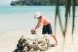 © Amber - man cuts open coconut on a deserted island in the tropics