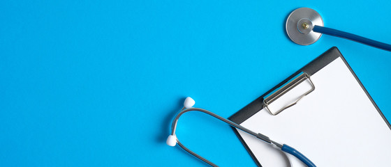 medical clipboard and stethoscope on blue background. medical banner template with copy space, heade