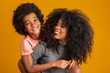 © Brastock Images - Portrait of young African American mother with toddler son. Yellow background. Brazilian family.