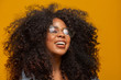 © Brastock Images - Beauty portrait of african american with glasses and afro hairstyle on a yellow background. Brazilian young woman.