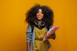 © Brastock Images - Female student in campus with books in her arms. Yellow background.