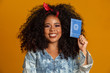 © Brastock Images - Beautiful curly-haired girl holding a work card. On yellow background.
